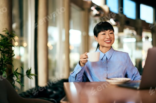 Preview: Asian Business Woman Enjoying Coffee While Working in a Modern Cafe