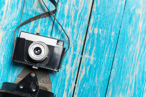 Preview: Vintage camera placed on a blue wooden surface in an indoor setting during the afternoon