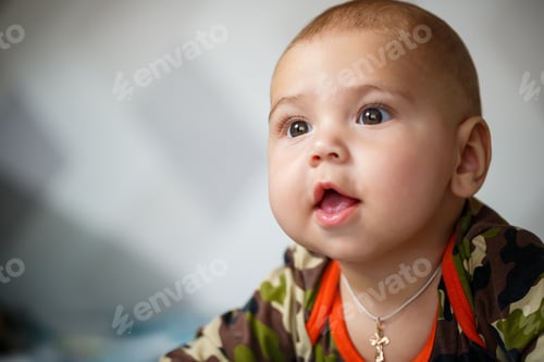 Preview: close-up portrait of a little boy age 8 months and is smiling. Dressed in military costume