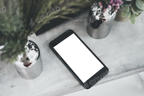 Preview: top view blank white screen mobile on concrete table with plant