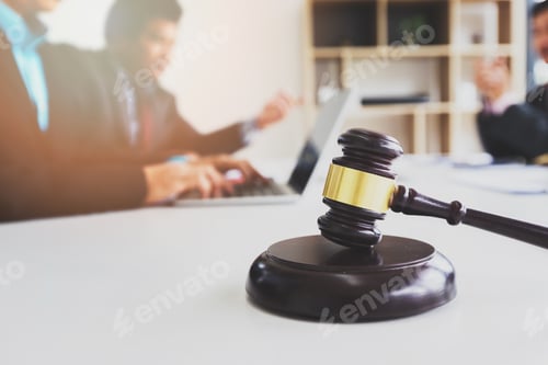 Preview: Wooden gavel on table in lawyer's office. Lawyer having team meeting with the client.