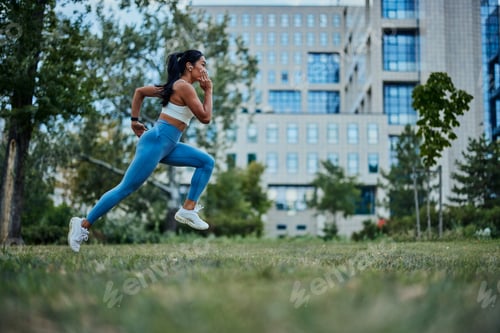 Preview: Young and athletic woman running through the park