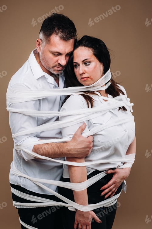 Preview: An aggressive man embraces a battered woman and is wrapped in bandages together. Domestic violence