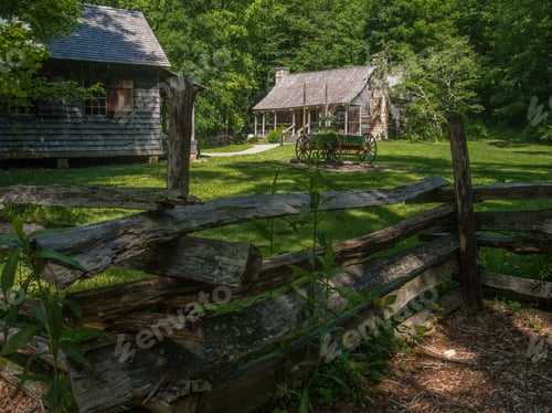 Preview: Small rural houses in the forest with wooden fence in the foreground