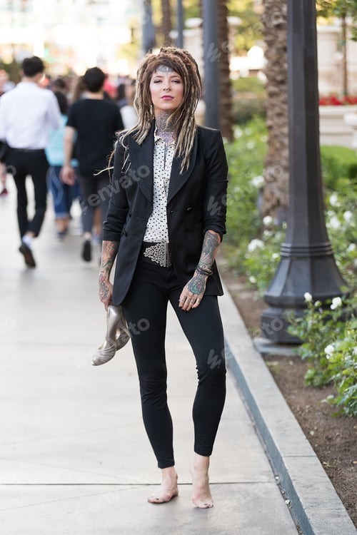 Preview: Businesswoman with tattoos and dreadlocks wearing her shoes and walking barefoot