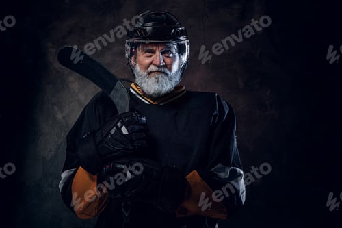Preview: Aged hockey player dressed in black sportswear holding stick