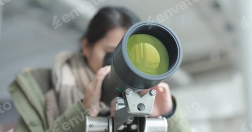 Preview: Woman looking through telescope to observe the bird habitat