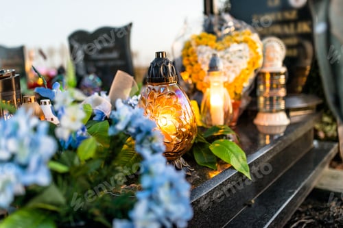 Preview: Artificial and real flowers and lit candles lying on the tombstone in the cemetery.