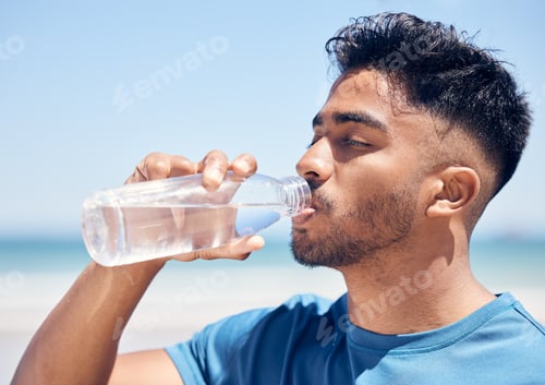 Preview: Shot of a man drinking water while out for a run on the beach