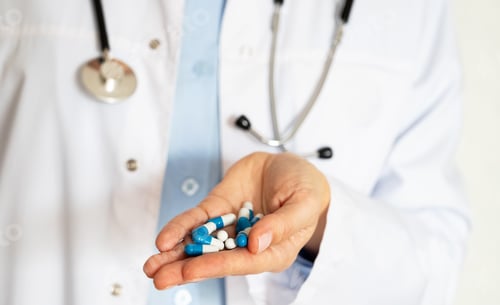 Visualização: Profissional médico segura medicamentos na palma da mão em ambiente clínico durante o dia