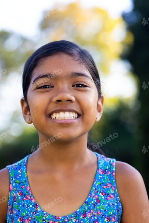 Visualização: Ao ar livre, jovem garota birracial sorrindo brilhantemente, usando vestido floral colorido