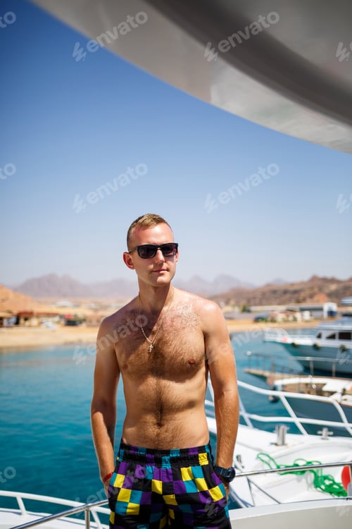 Preview: Successful guy sit on a white yacht with sea view. Red sea, bright sun