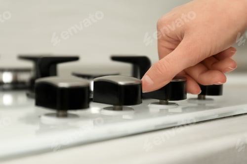 Preview: Woman regulating cooking mode on gas stove panel, closeup