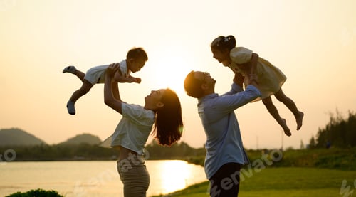 Preview: Happy father and mother holding children playing together in park