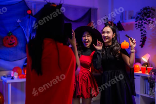 Preview: Friends celebrating Halloween party, taking selfie with witch costumes and festive decorations