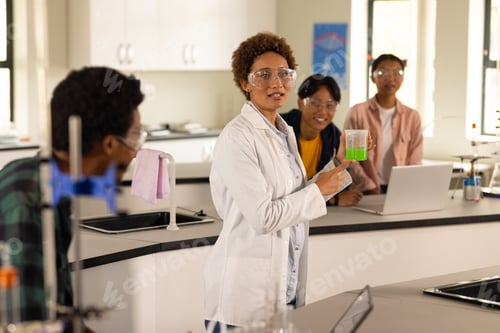 Preview: In high school laboratory, teacher demonstrating experiment with beaker to students