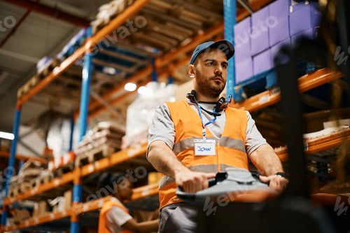 Preview: Male worker using pallet jack while working at distribution warehouse.