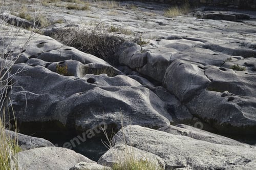 Preview: High angle shot of a smooth rocky surface with grown grass