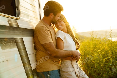 Preview: White couple hugging and smiling while standing by trailer