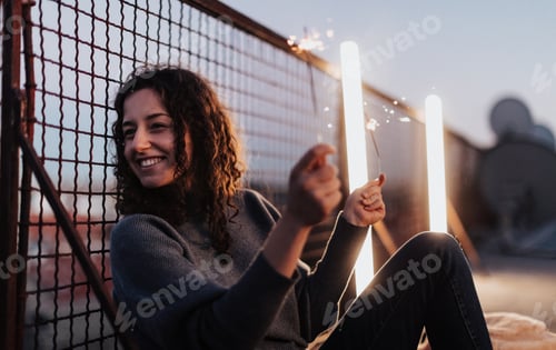 Preview: Young woman with sparklers having fun at rooftop in the city, close up.