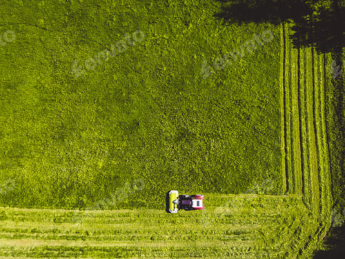 Preview: Top down view of a tractor mowing a grass field in straight lines all around