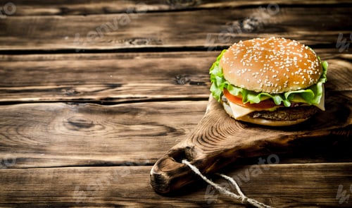 Preview: delicious Burger with meat , cheese and vegetables on wooden Board.