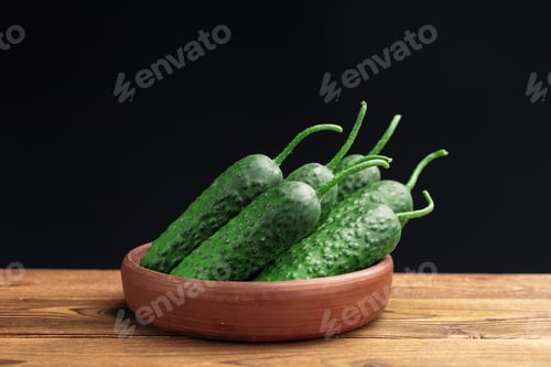 Preview: Fresh green cucumbers in a wooden bowl on a dark background