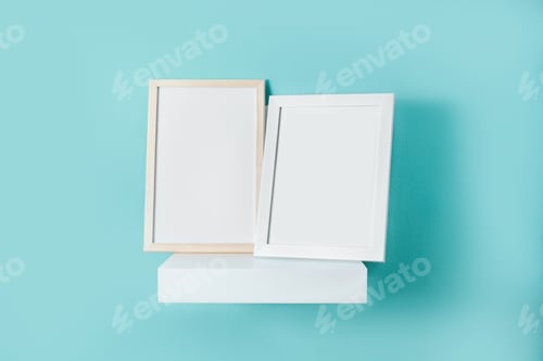 Preview: Two empty frames leaning on shelf against turquoise wall