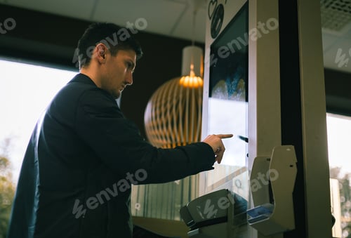 Preview: A young man makes an order for fast food on a scoreboard screen in a diner.
