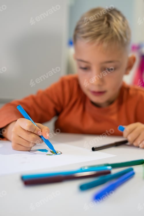 Preview: Young child drawing with markers, concentrated on creativity and art