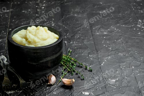 Preview: Mashed potatoes in a bowl with garlic and thyme.