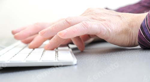 Preview: Hands of an old female typing on the keyboard, isolated on white, close-up