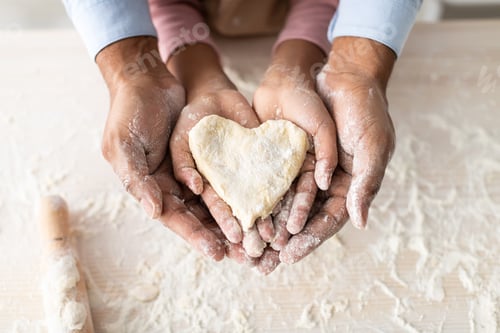 Preview: Black man and girl holding dough in heart shape