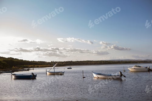 Preview: Tranquil lake scene with moored boats at sunset