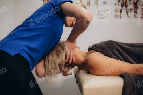 Preview: Physiotherapist helping senior woman with elbow exercise in clinic. Doctor checking elbow