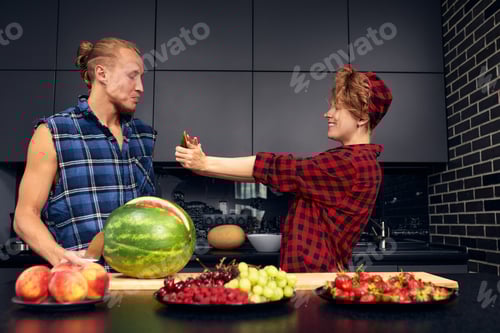 Preview: Happy couple standing in kitchen at home preparing together yummy dinner on first dating, spouses