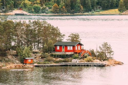 Preview: Sweden. Many Beautiful Red Swedish Wooden Log Cabin House On Rocky Island Coast In Summer. Lake Or