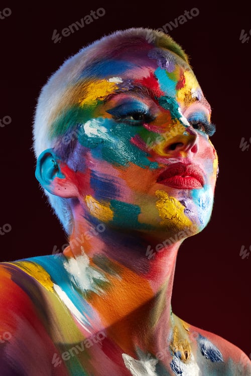 Preview: Studio shot of a young woman posing with multi-coloured paint on her face
