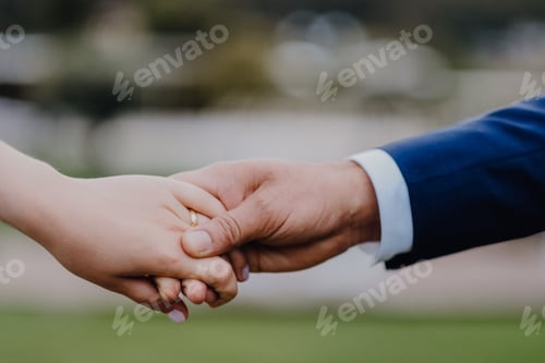 Preview: Shallow focus shot of the bride and the groom holding hands