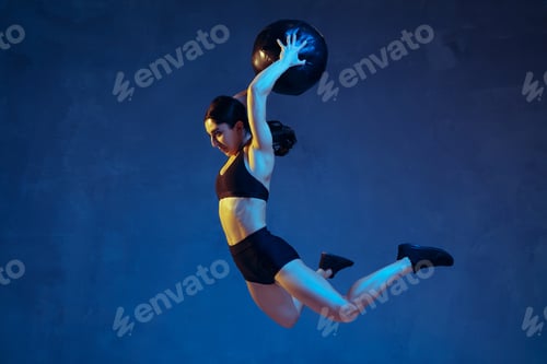 Preview: Caucasian young female athlete practicing on blue studio background in neon light