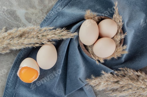Preview: Cracked raw egg on marble background with cloth