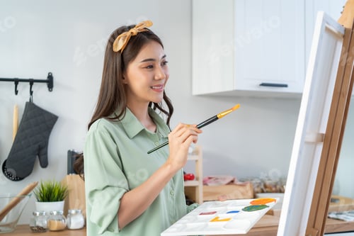 Preview: Asian young talented woman artist coloring on painting board, enjoy creativity activity at home.