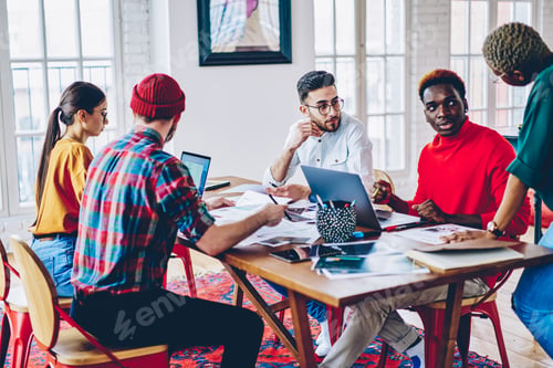 Preview: Youthful hipster coworkers discussing developing project during desktop brainstorming indoors
