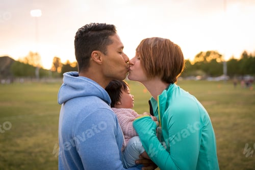 Preview: Couple with baby, kissing in park