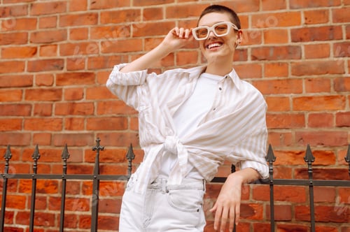 Preview: Portrait of a young woman with a short haircut posing on the city streets. Urban concept.