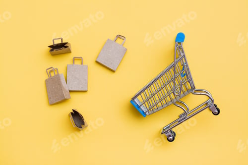 Preview: Eco-friendly craft paper bags next to a metal shopping cart on a yellow background.