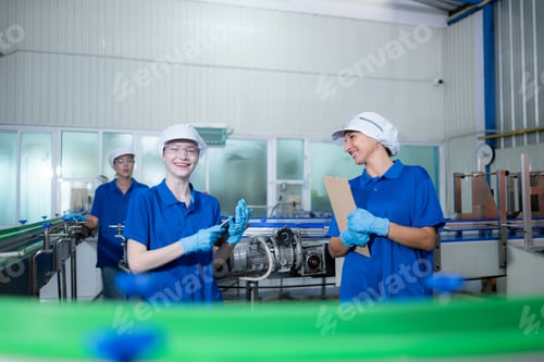 Preview: Young woman factory workers in blue uniforms and hats working together in drinking water factory