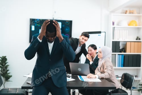 Preview: Frustrated African American businessman stressed and overwhelmed in meeting room after facing