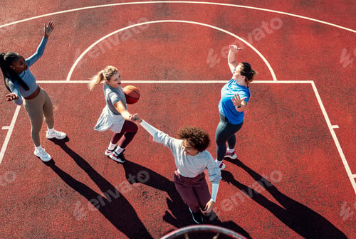 Preview: Diverse group of young woman having fun playing basketball outdoors.
