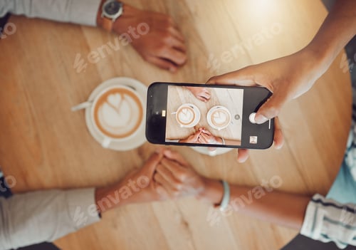 Preview: Close up of device screen while couple holds hands with two cups of coffee on a wooden table while